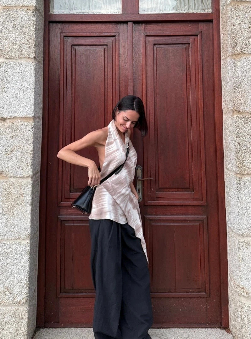 Woman wearing a black GREBELLA crossbody bag in front of a wooden door